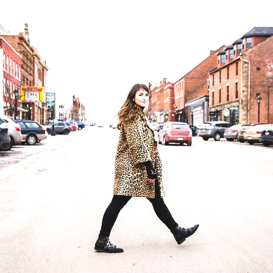 Hillary MacDonald, RSJ '14, wearing a leopard print jacket and walking across a street in PEI. 