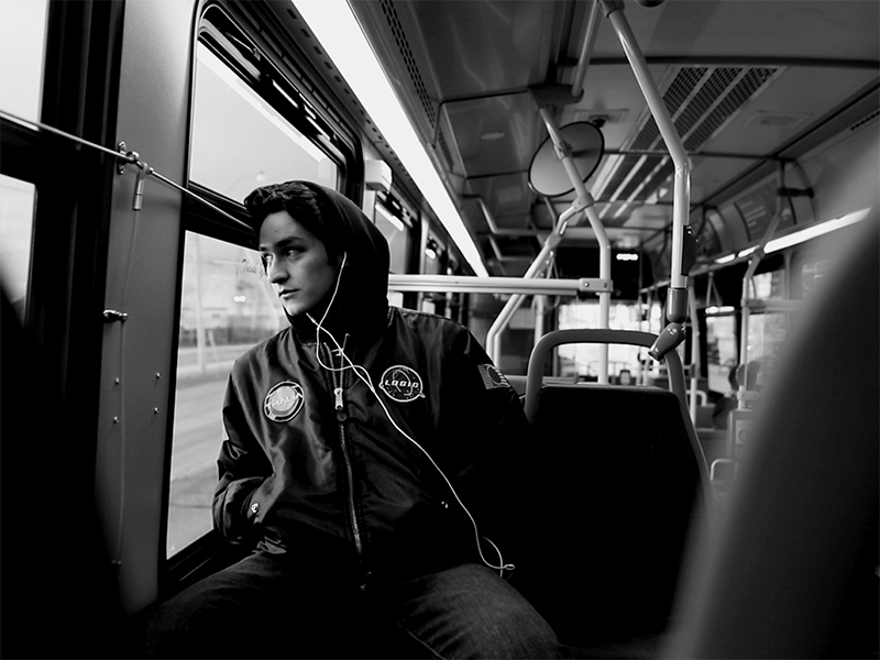Luke Galati looks out the window of a bus in this black and white photo. 