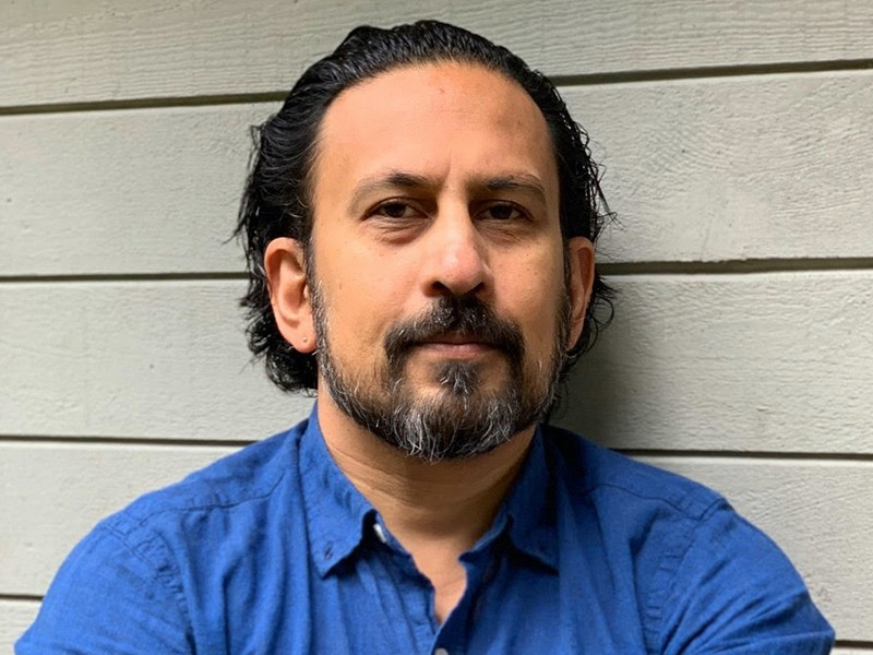 Ravindra Mohabeer against a white wood background. 