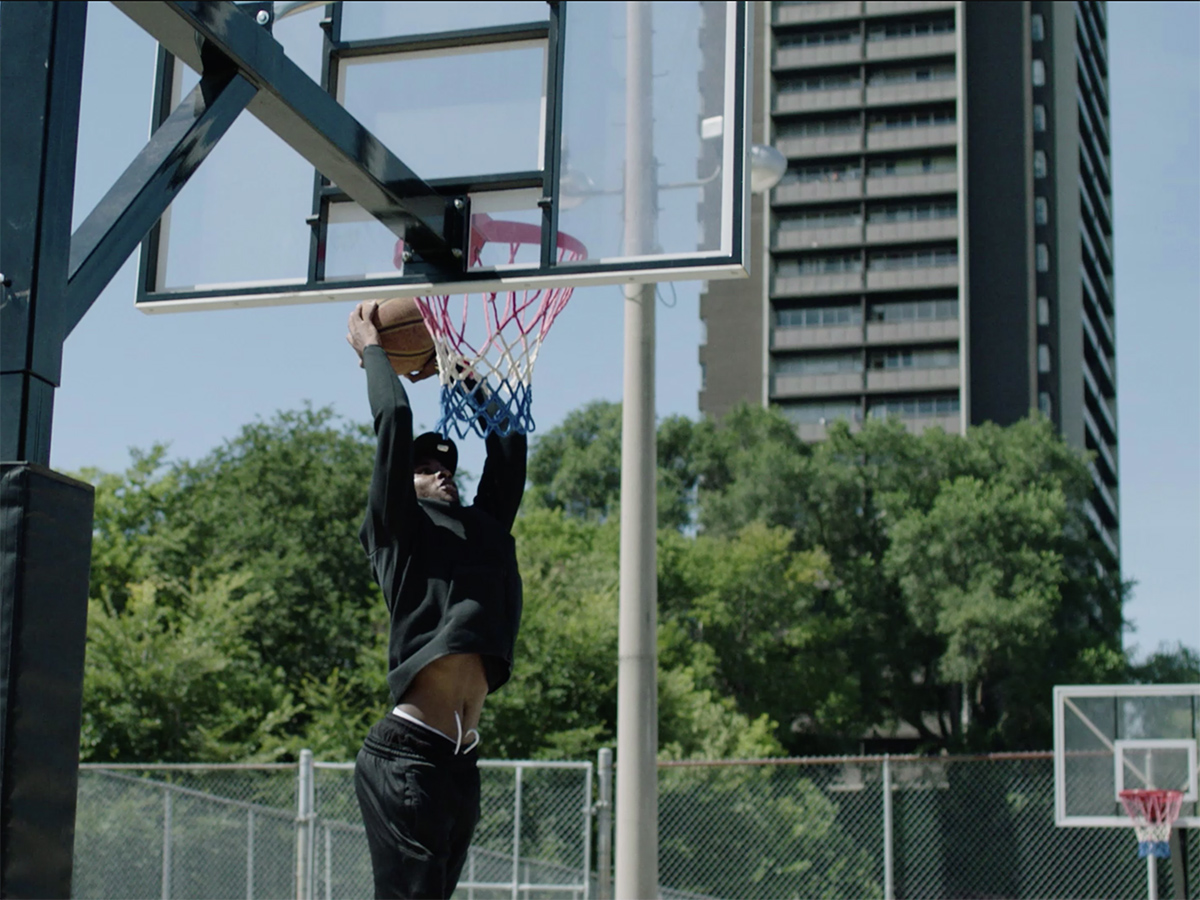 Still from the short film SMOKEYSWRLD. A basketball player is dunking. 