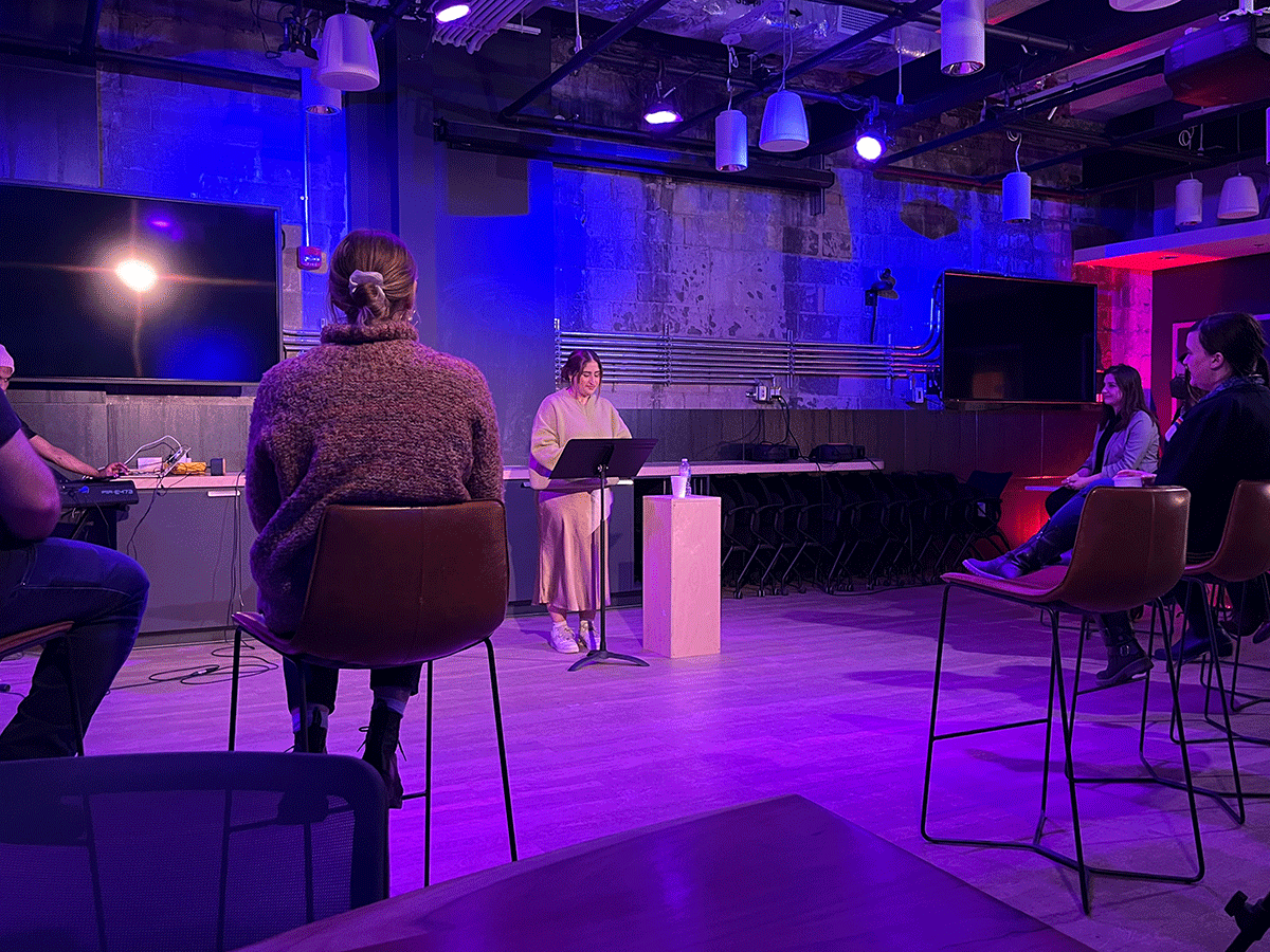 Dania Ali stands at a podium on stage at a live performance