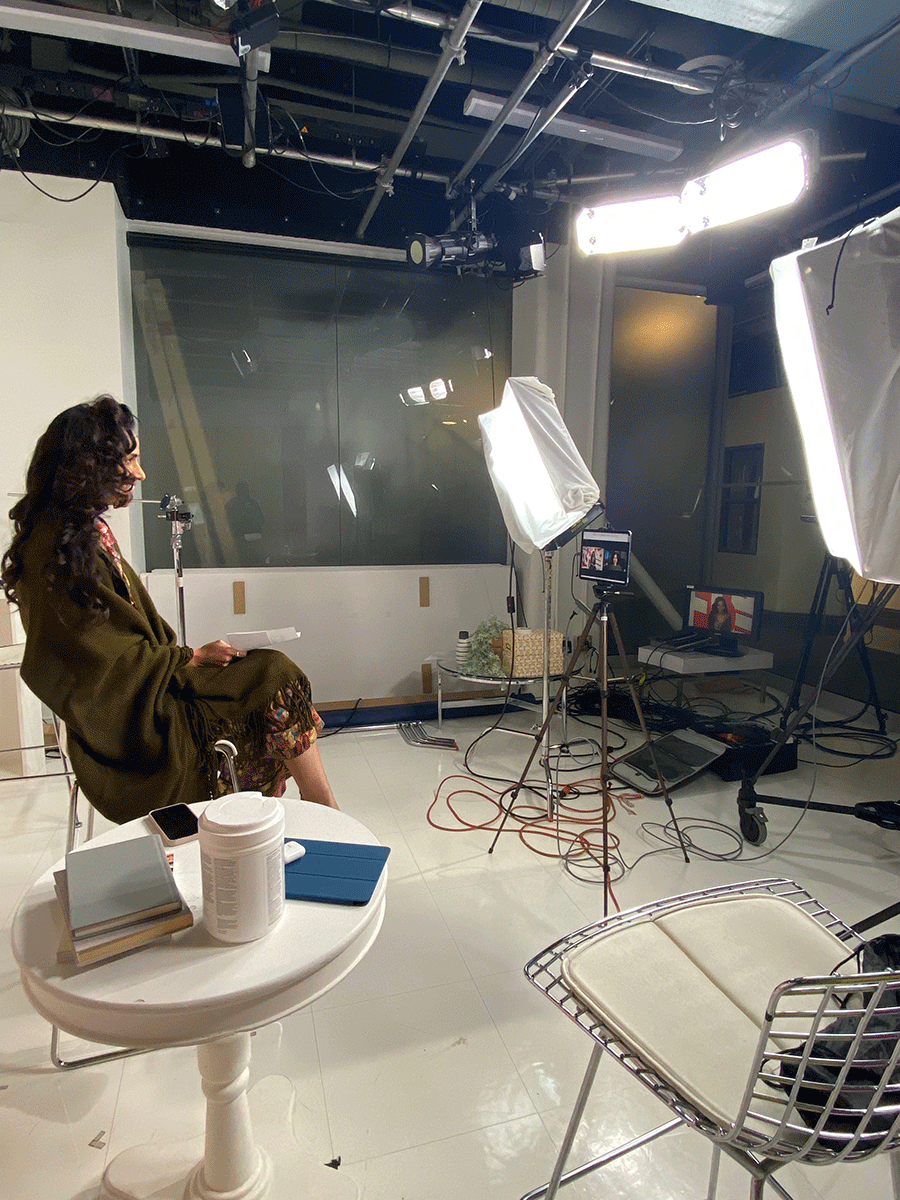 A woman sitting on a stool in a television studio.