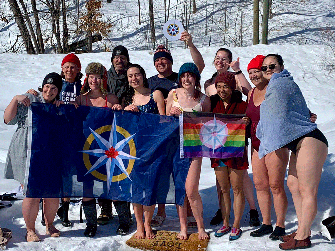 A group of people in the snow wearing bathing suits getting ready to take the polar plunge.