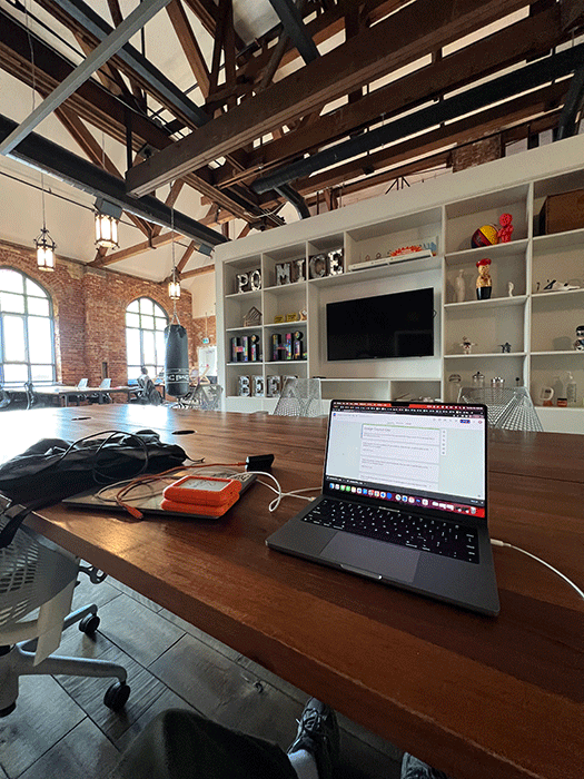 A laptop and orange hard drive sitting on a large desk.