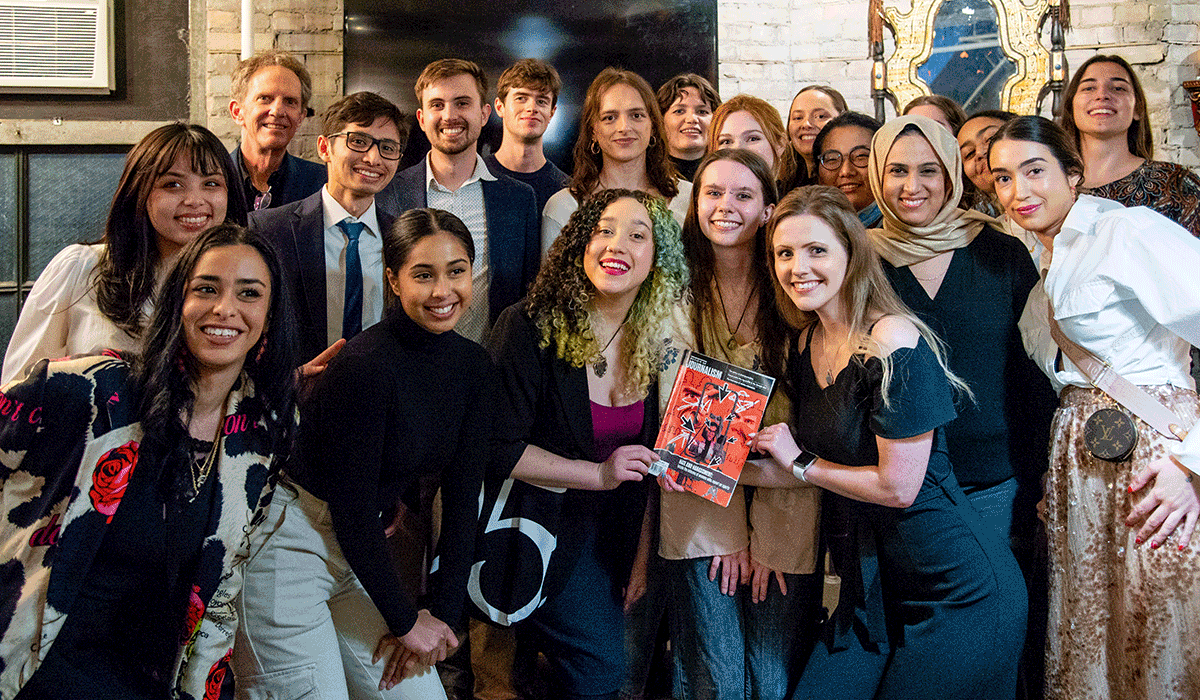 Students from the Review of Journalism masthead with their instructors posing for a group photo with the two students in the centre holding a copy of the magazine.