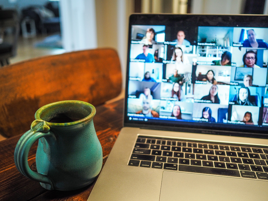 Green mug and a laptop with a Zoom meeting on the screen. 