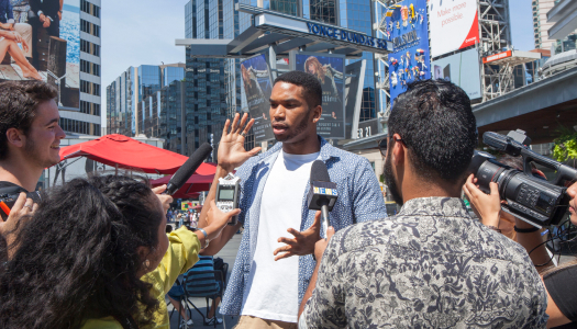 A young man answers questions from journalist at famous Toronto square