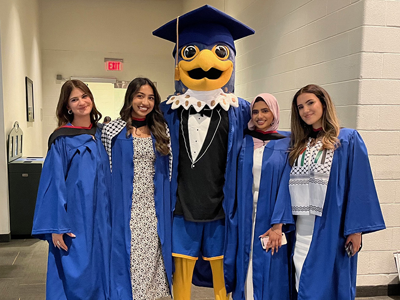 TMU J-school graduates pose with Frankie the Falcon after their convocation ceremony at the Mattamy Athletic Centre