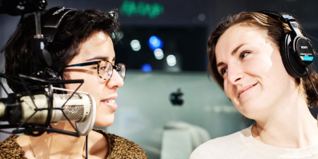 Two students working with mic and headphones in a production studio