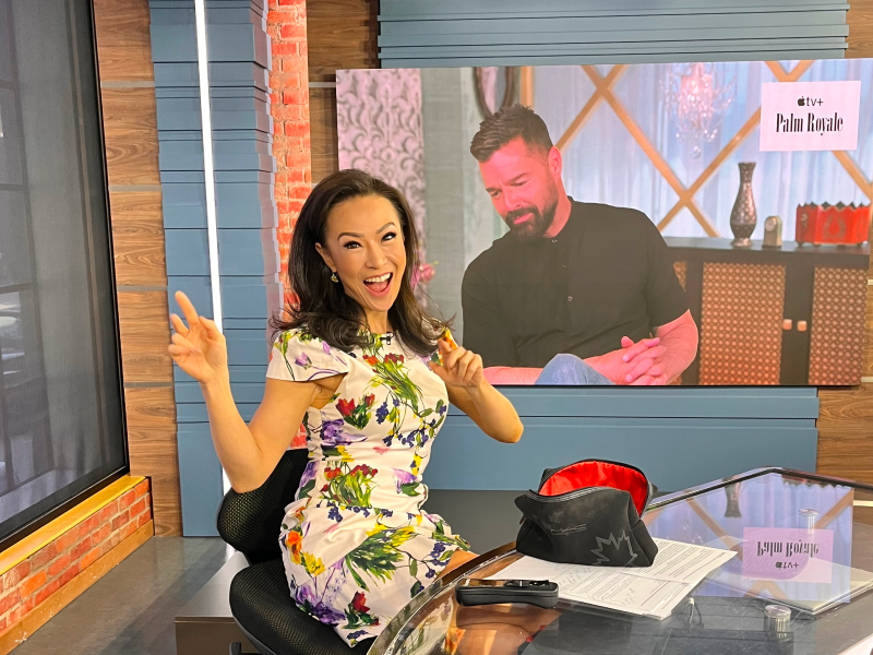 Jennifer Hsiung sits at a news desk smiling at the camera