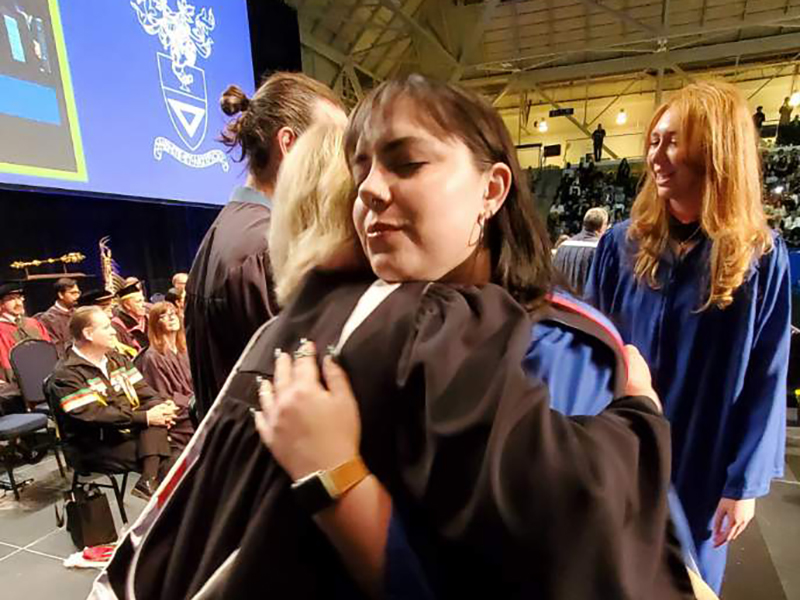 School of Journalism 2023 graduate hugs Janice Neil while exiting the stage.