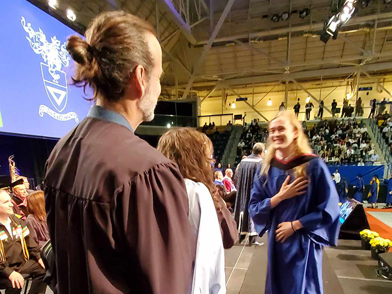 School of Journalism 2023 graduate looks towards faculty while walking across the stage.