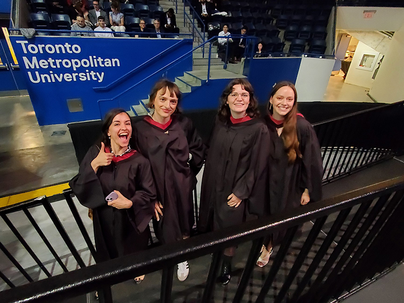 Four School of Journalism 2023 Masters graduates pose together off stage.