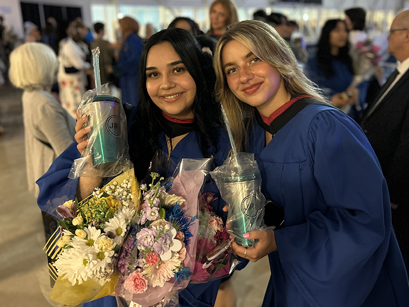 Two School of Journalism 2023 graduates stand together.