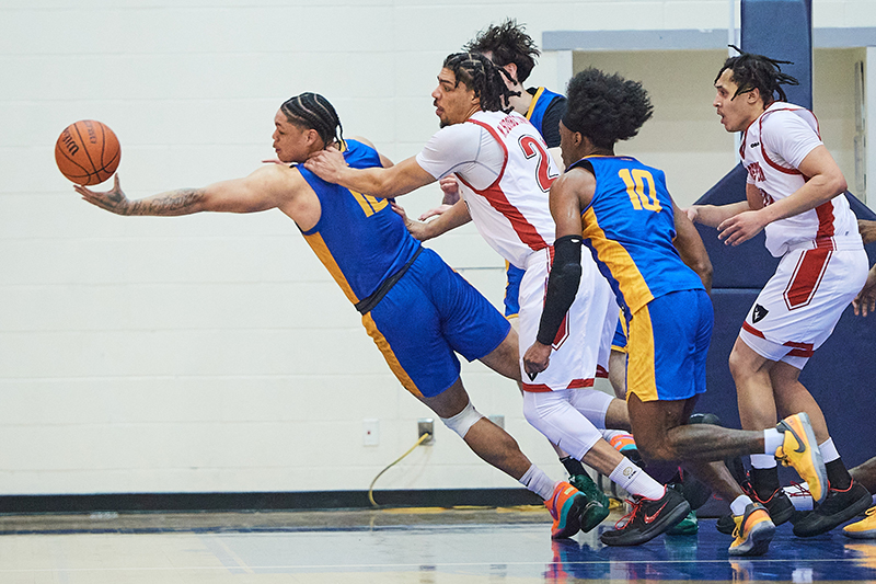 A tense photograph of two basketball teams reaching for the ball.