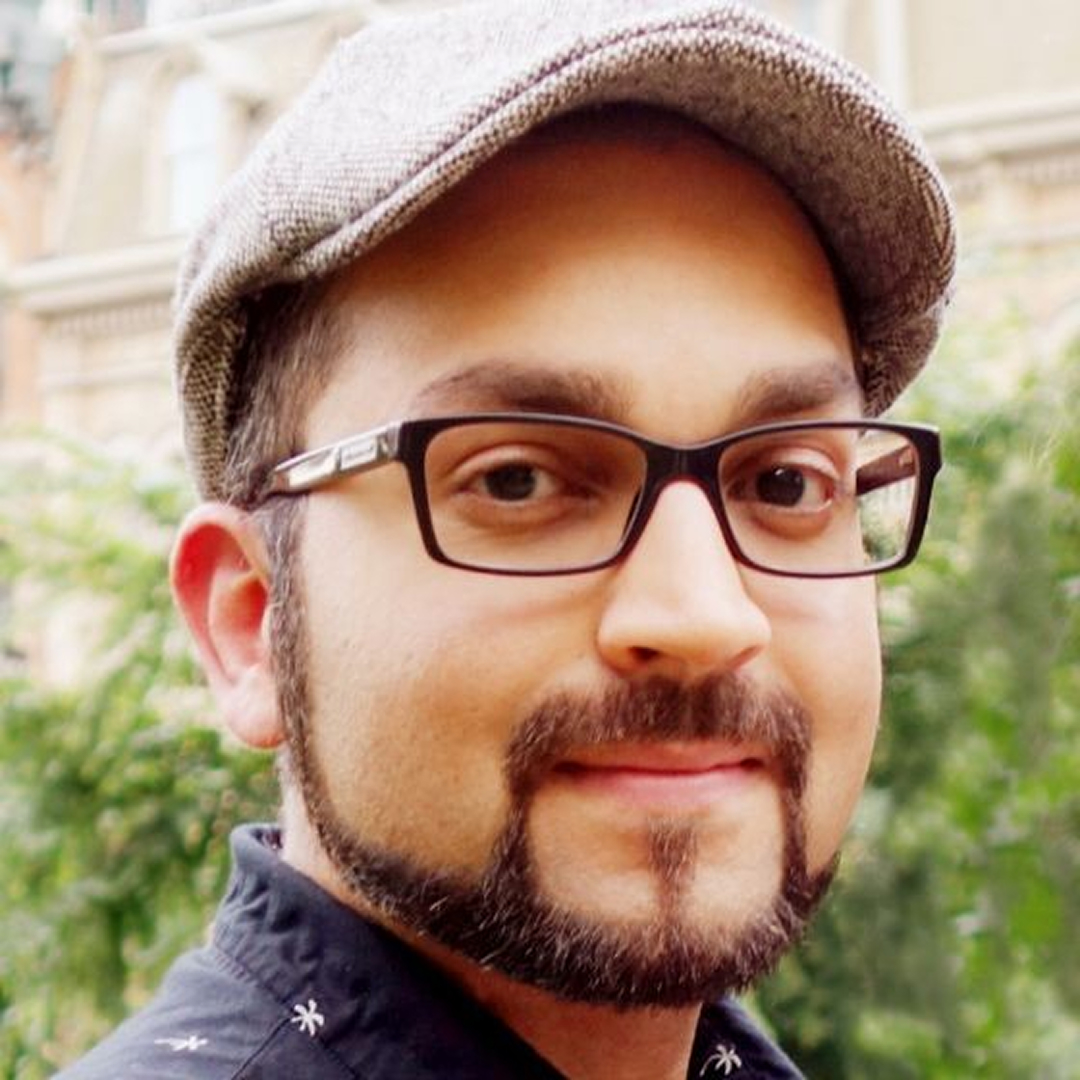 Headshot of Aneesh Tiberias Murali wearing a hat and glasses smiling