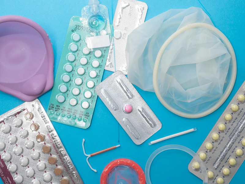 Various forms of contraception scattered on a light blue background