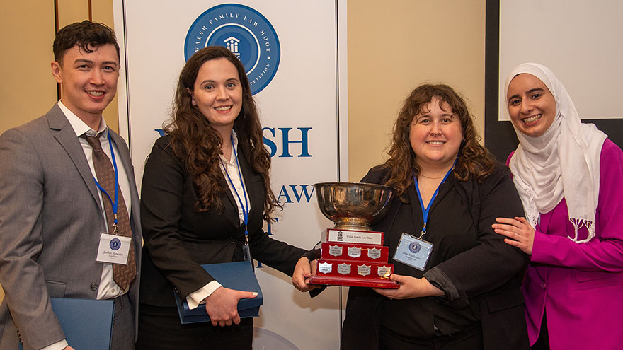 woman holding her awards trophy beside friends at awards ceremony