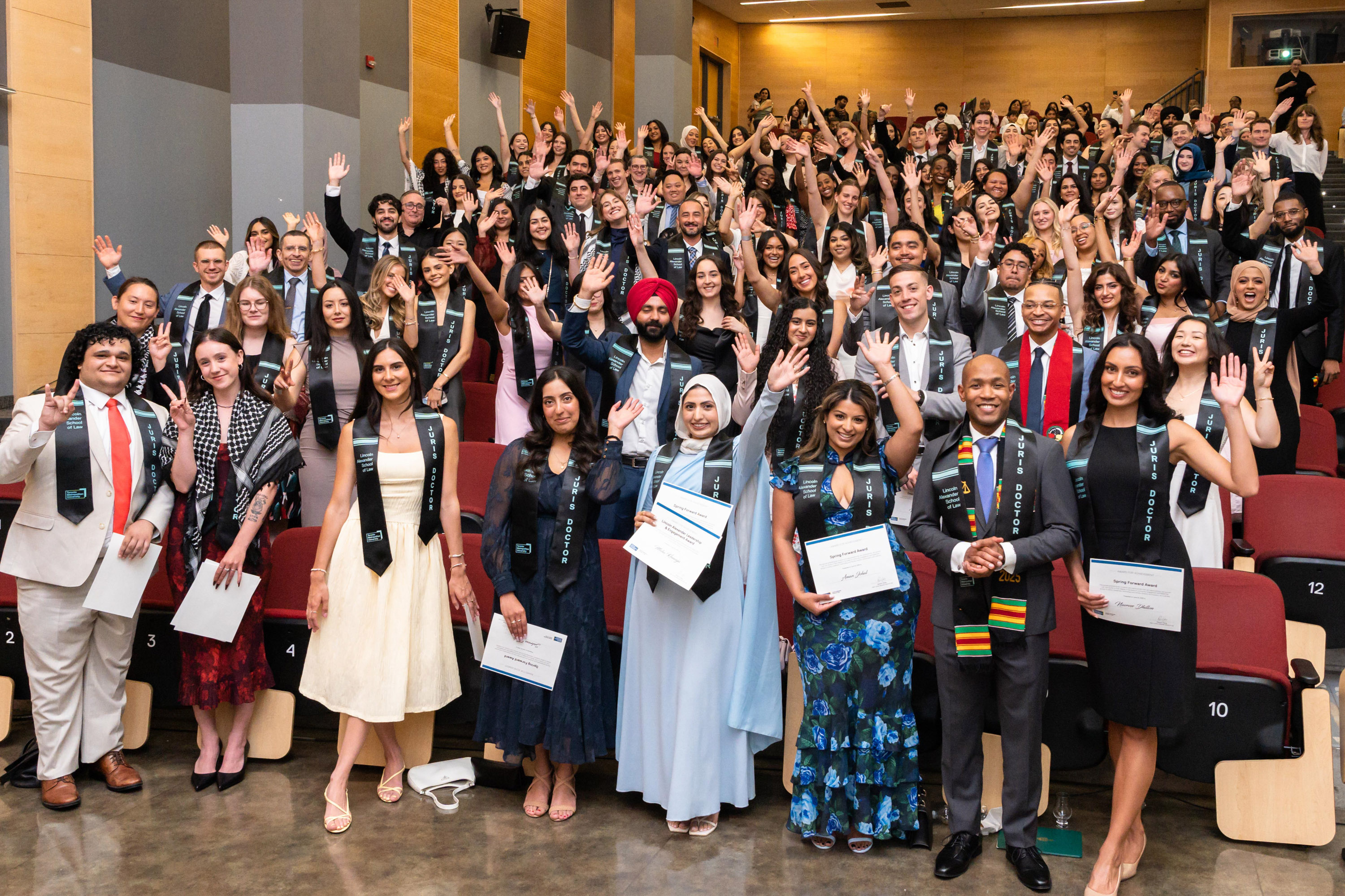 class waving from the auditorium after ceremony