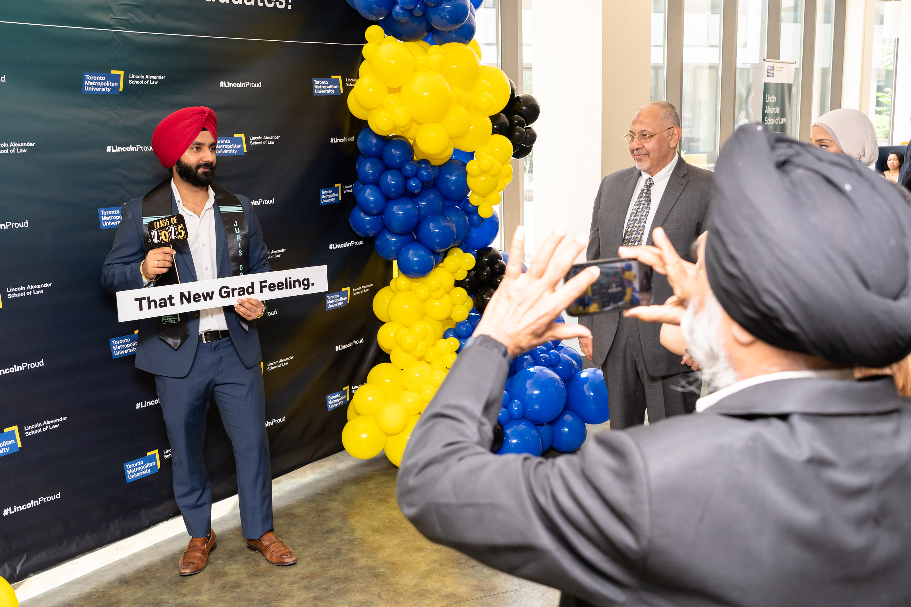 proud male grad posing by balloons