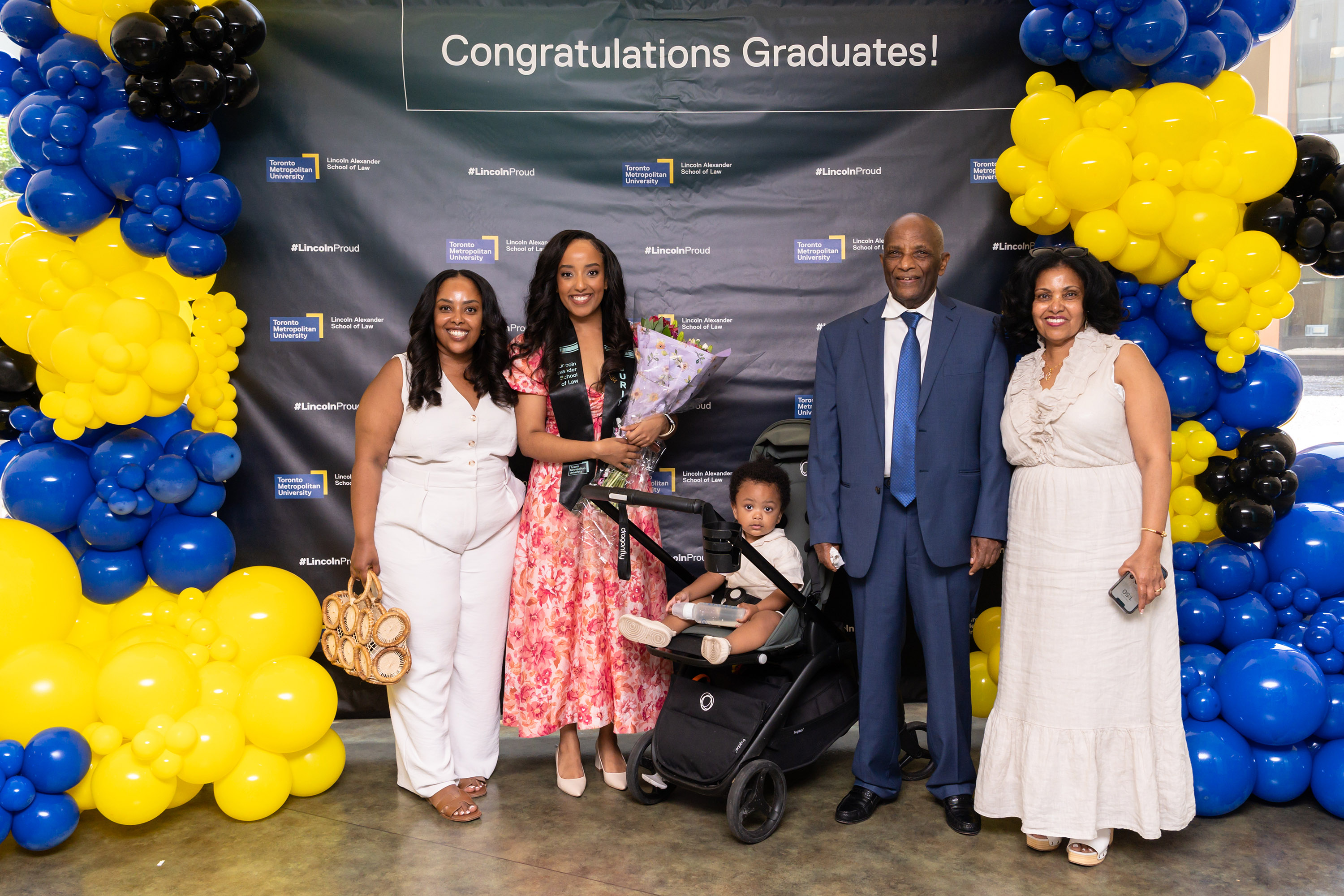 grad posing with family at balloon sign