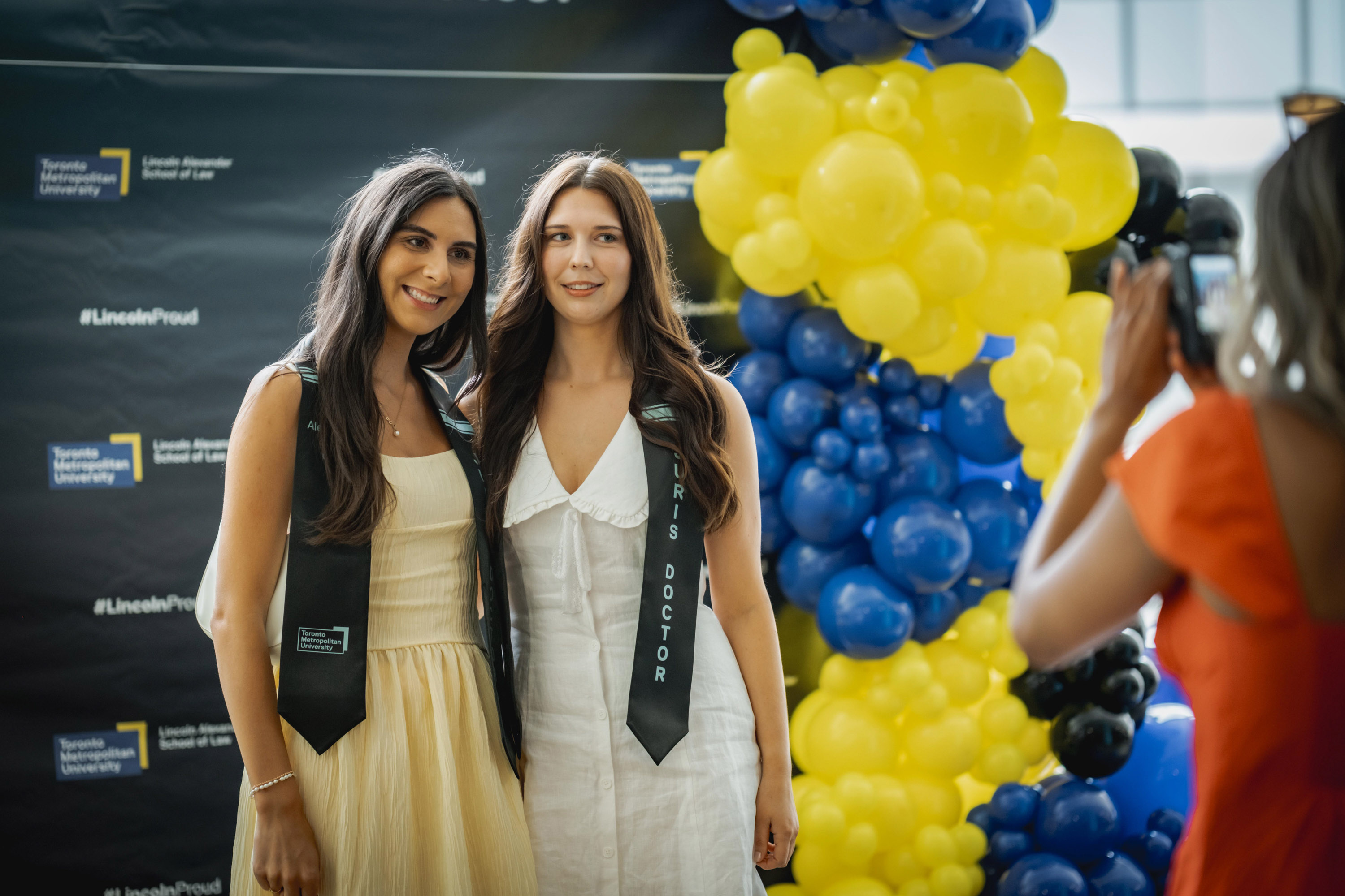 two female grads posing at balloons