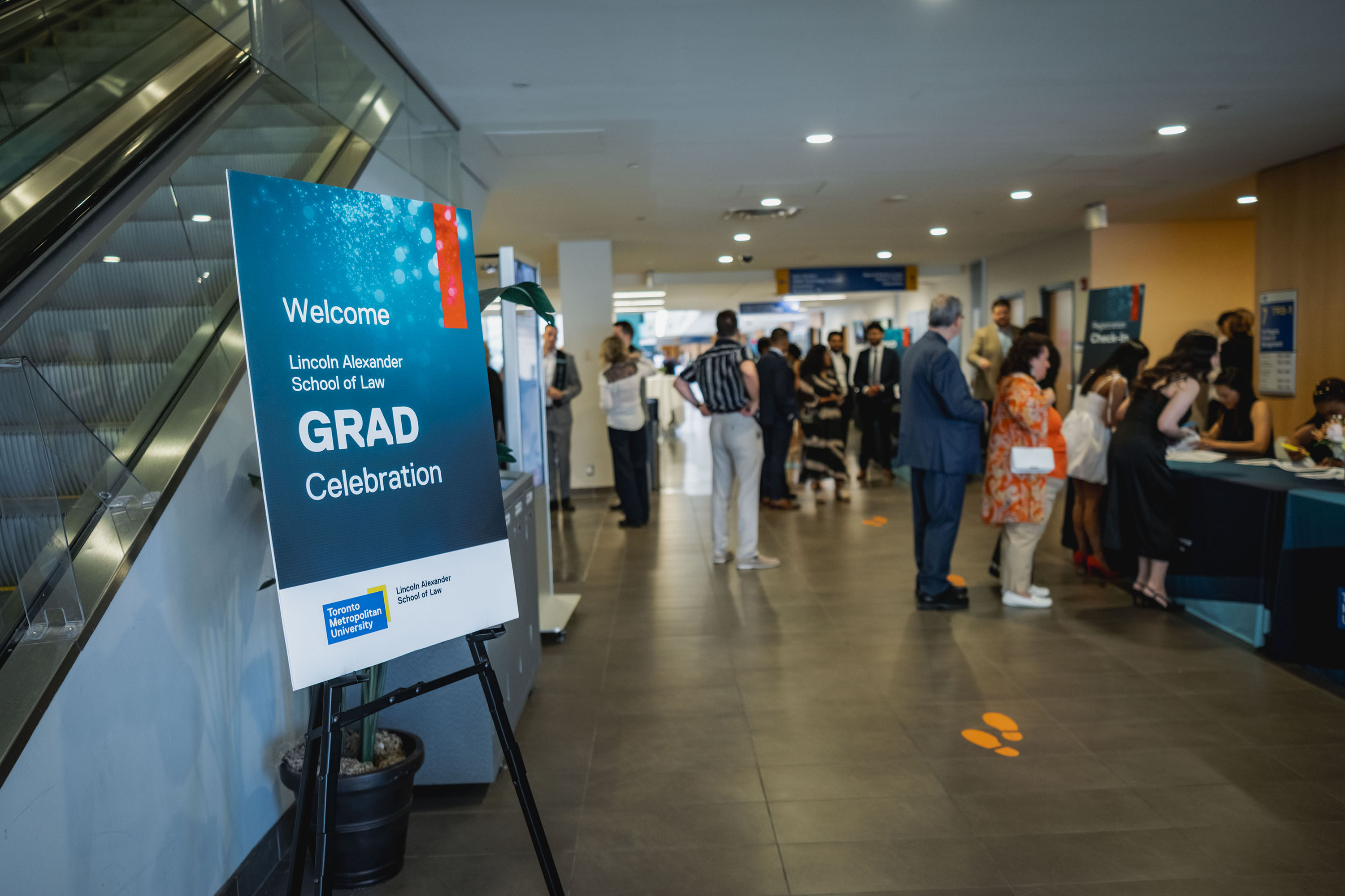 grad celebration welcome sign with attendees in the background