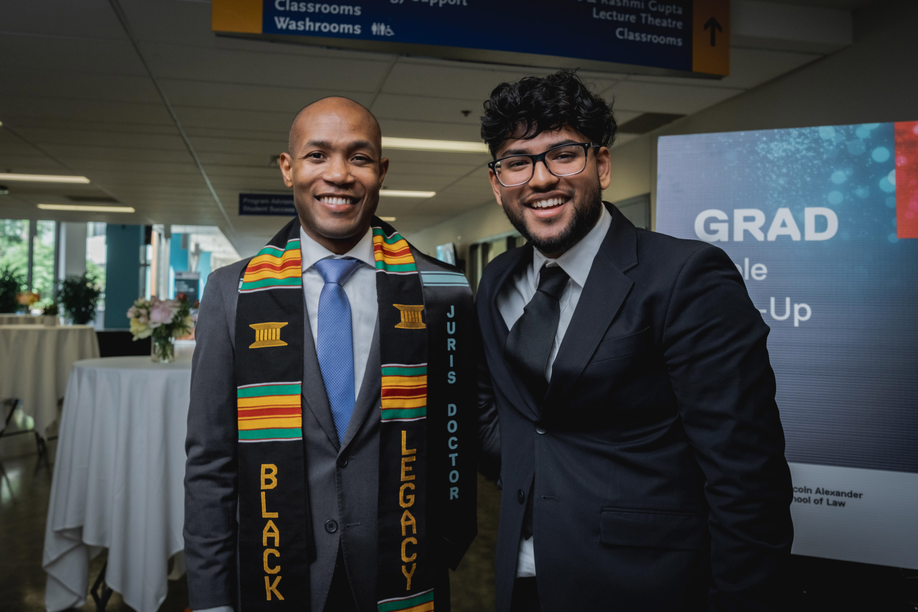 two men smiling for camera in hallway