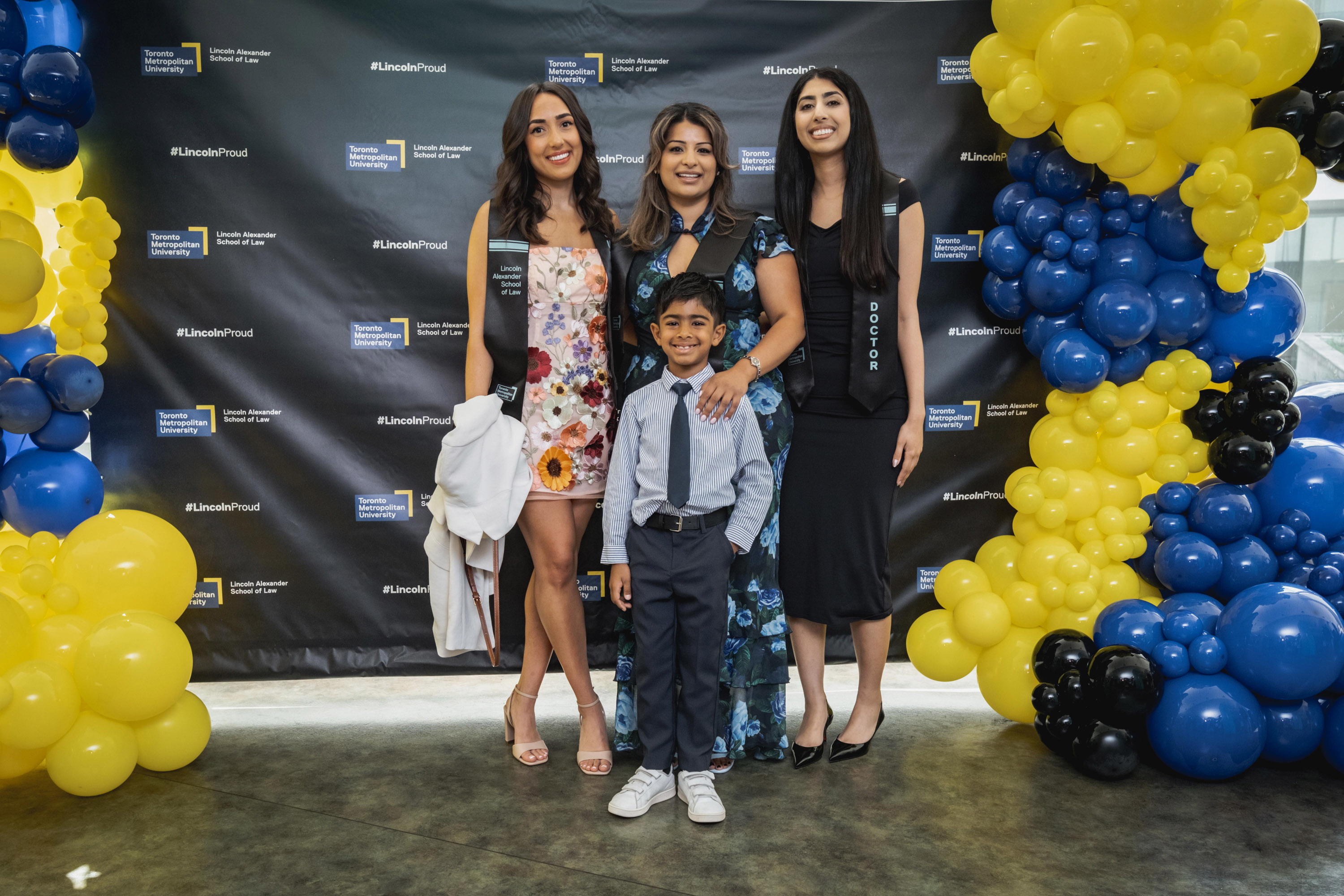 grad and family posing at grad sign with balloons