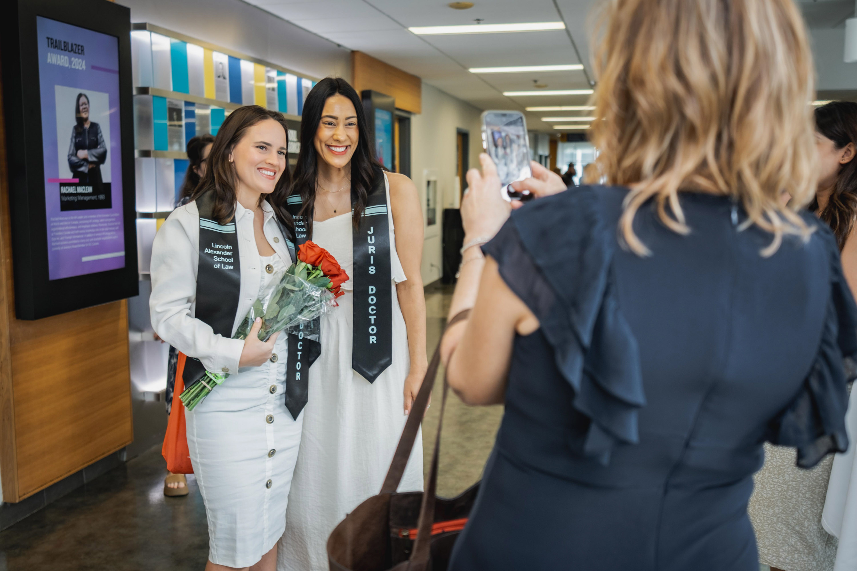 two female grads getting photo taking by family