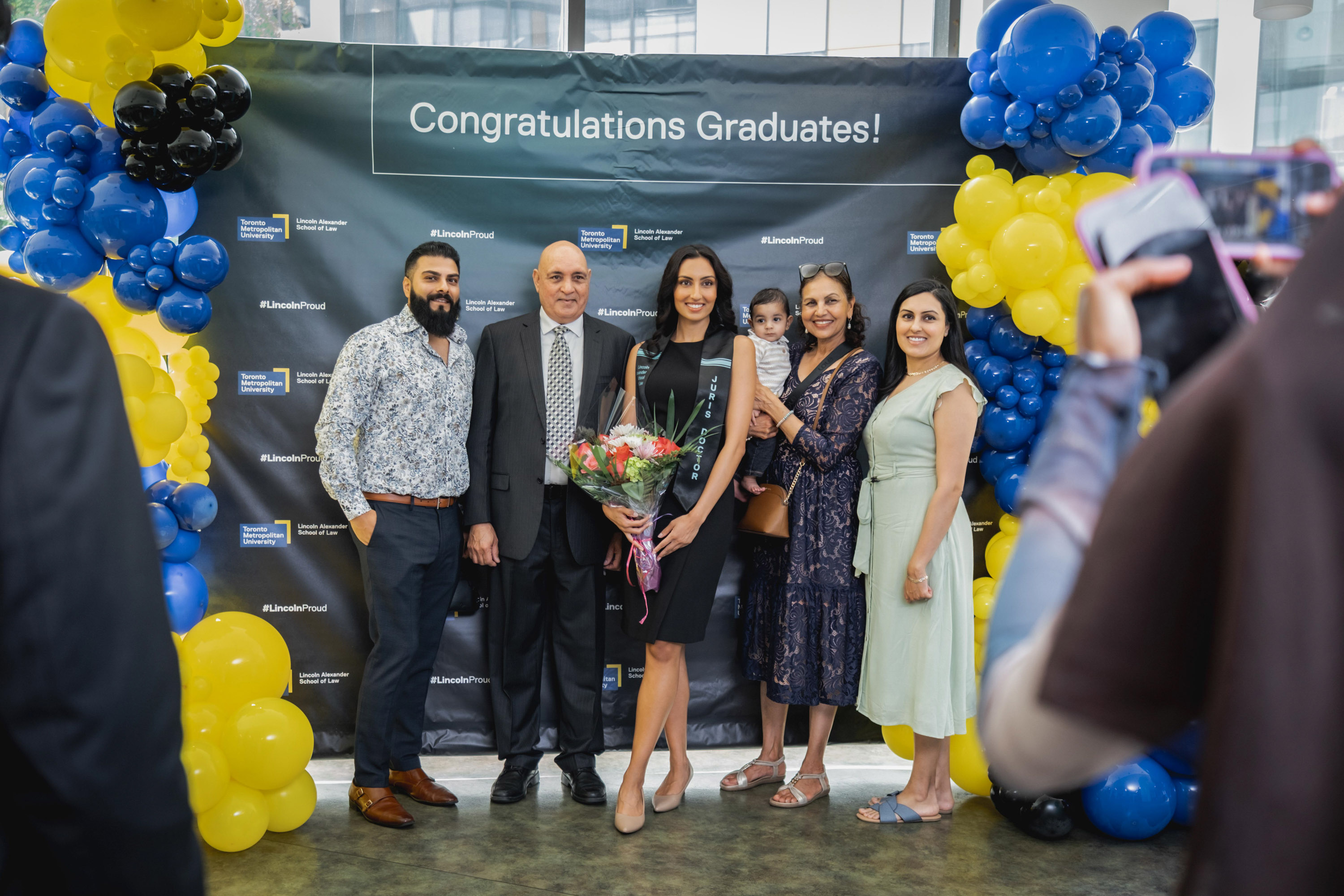 grad with family posing at sign and balloons