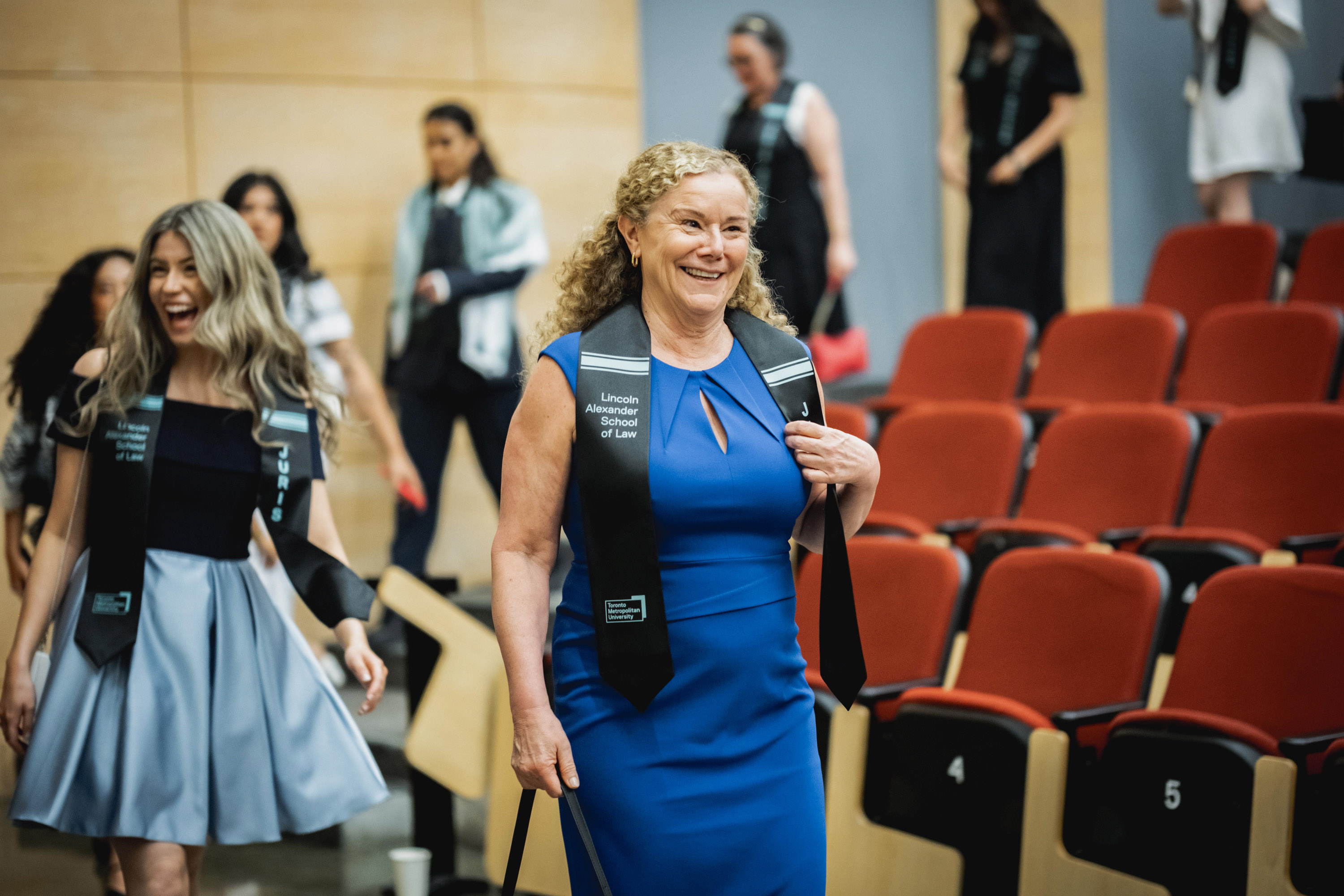 grad smiling as she walks out of auditorium at end of celebration
