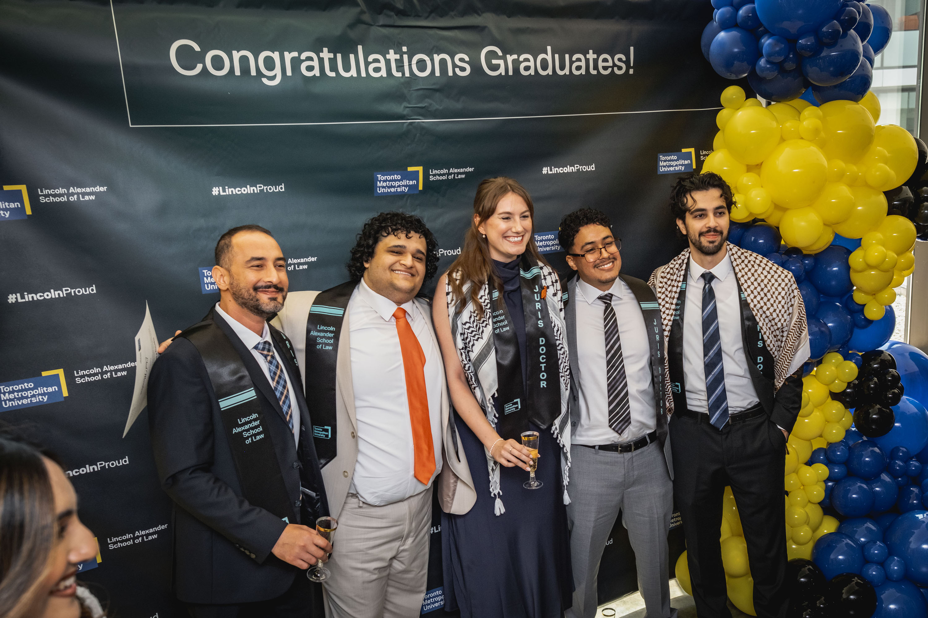 grads pose in front of photo-wall and balloons