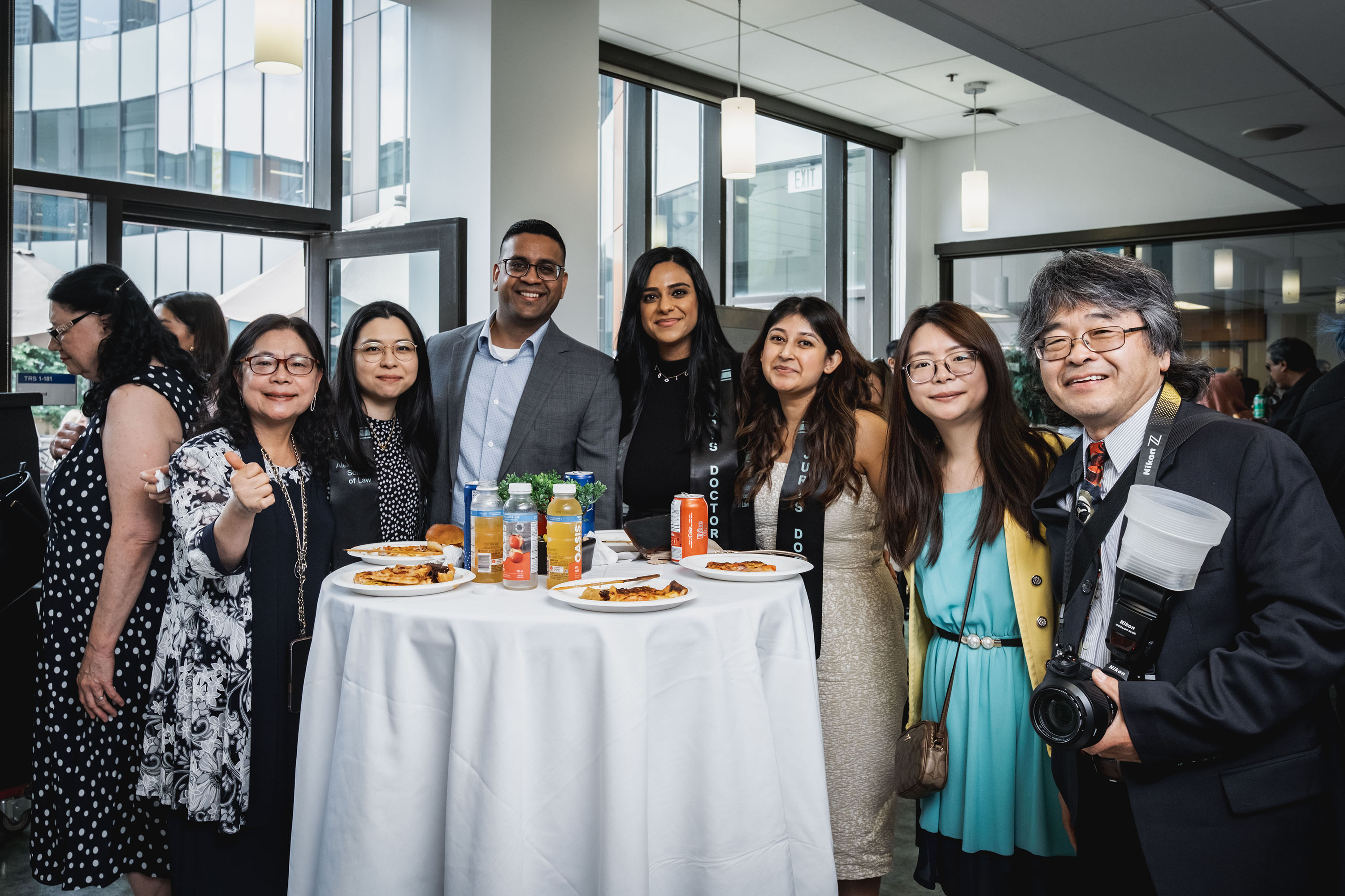 grads and their guests stand smiling around a table