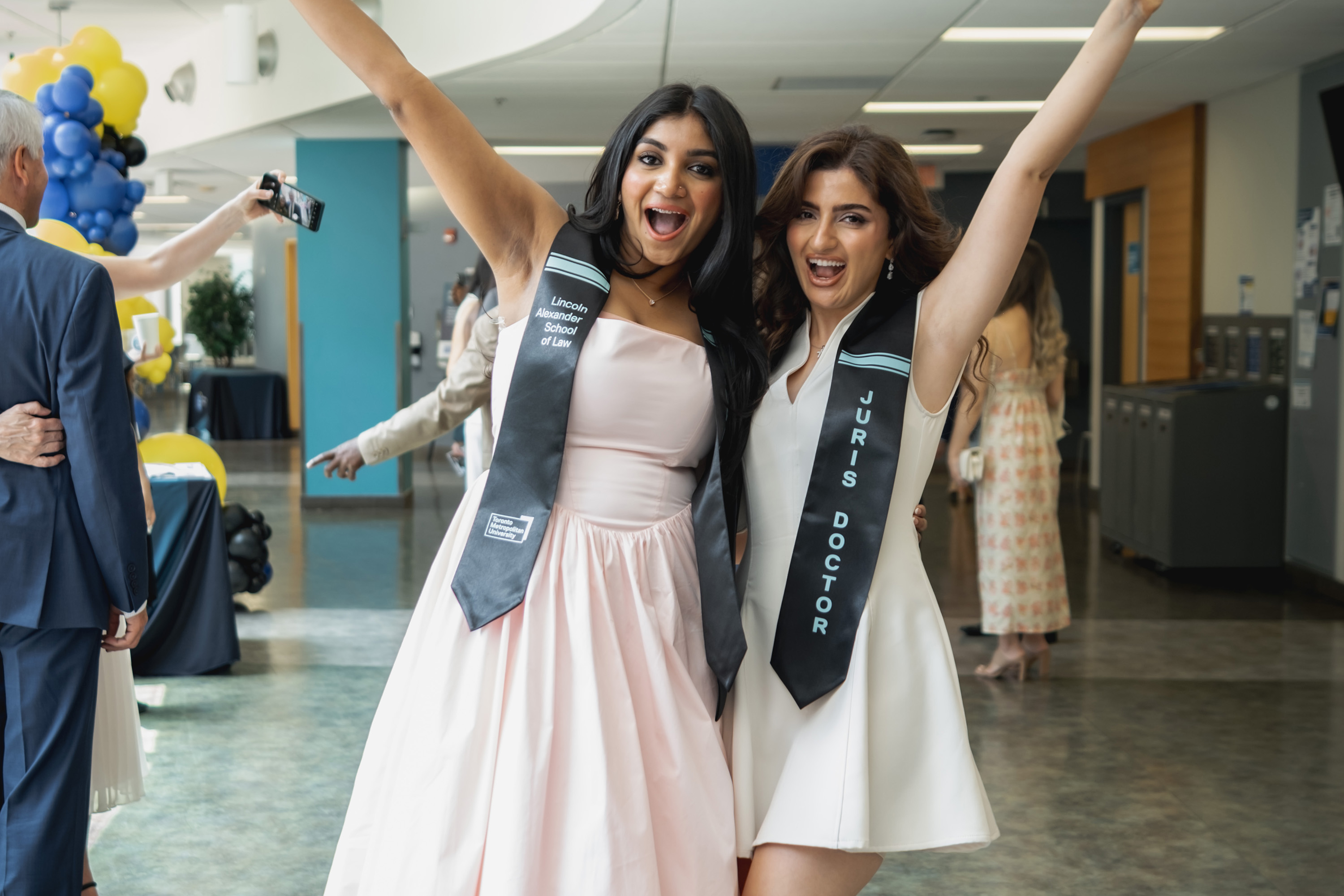two graduates pose excitedly for a photo