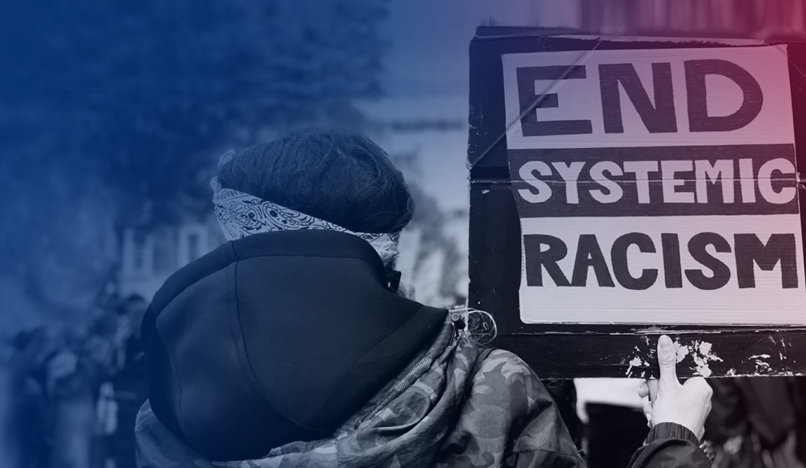 Street protester holding a sign 'End Systemic Racism'.