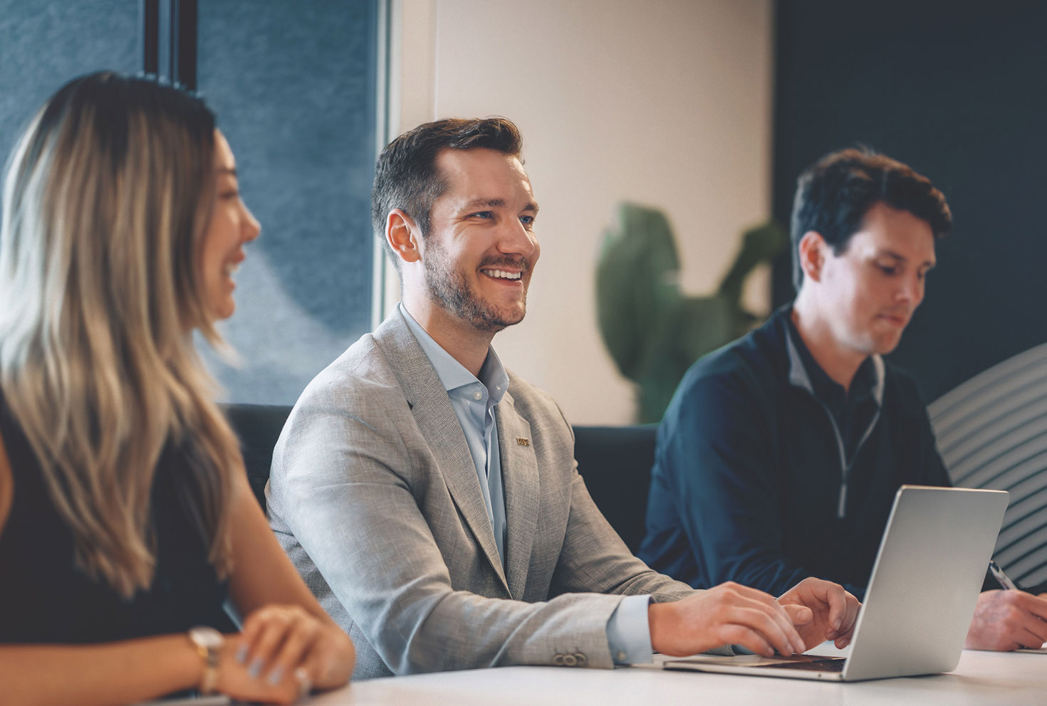 3 people in a meeting with their lapptop smiling