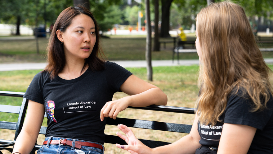 two students talking while sitting on bench