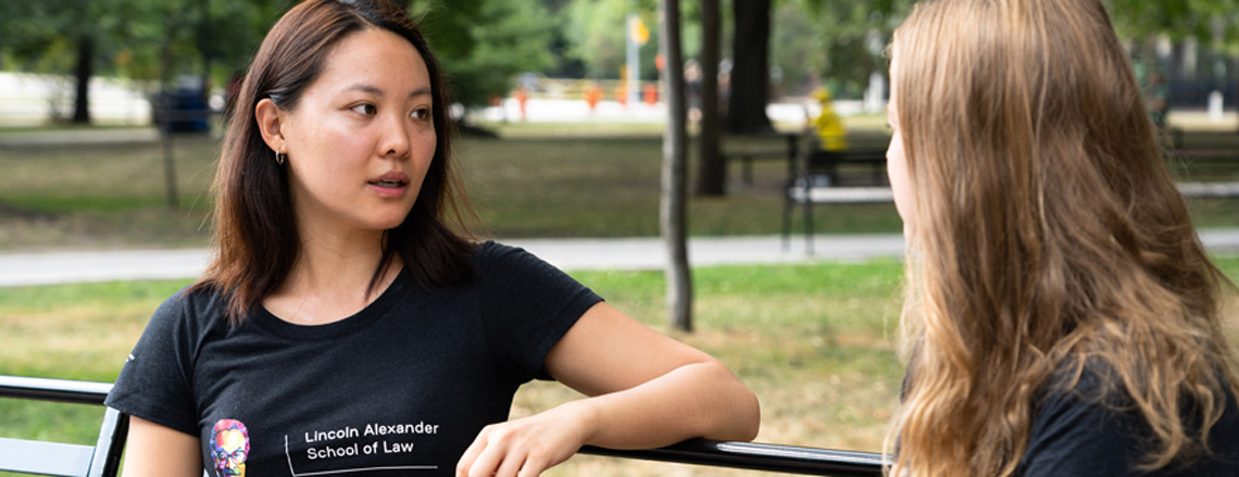 2 students talking and sitting on a park bench