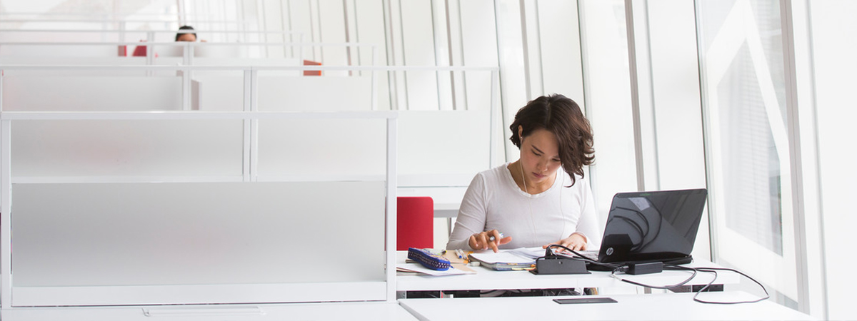 A person studying by their laptop, in an empty study space.