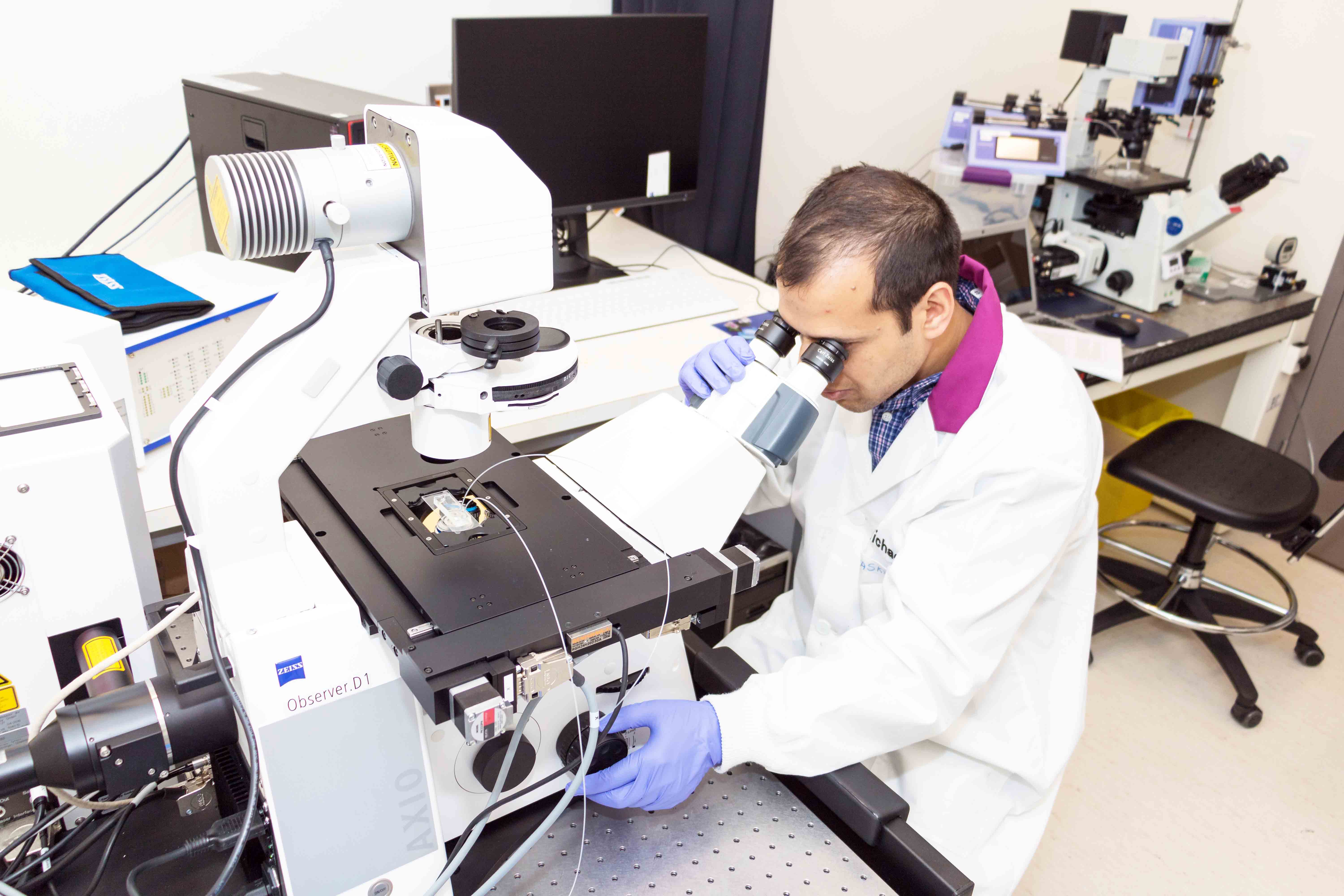 A student using an optical microscope in the laboratory.