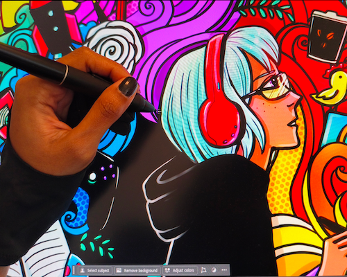 "A close-up view of an artist's hand using a stylus to draw on a digital tablet. The screen displays a vibrant, colorful illustration of a profile of a person with light blue hair wearing red headphones and glasses, surrounded by detailed pop-art style doodles."