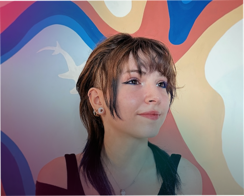 Hannah Nicoletta smiles while standing in front of a colorful abstract mural with flowing shapes and lines.