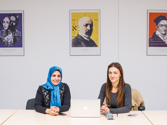 Two math gradaute students sitting at a meeting desk with laptop in fron tof them.