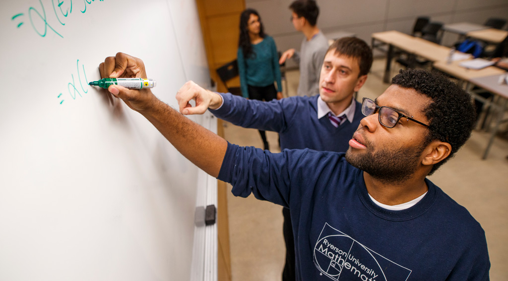 Financial math undergraduate student working on math problem in class with professor.