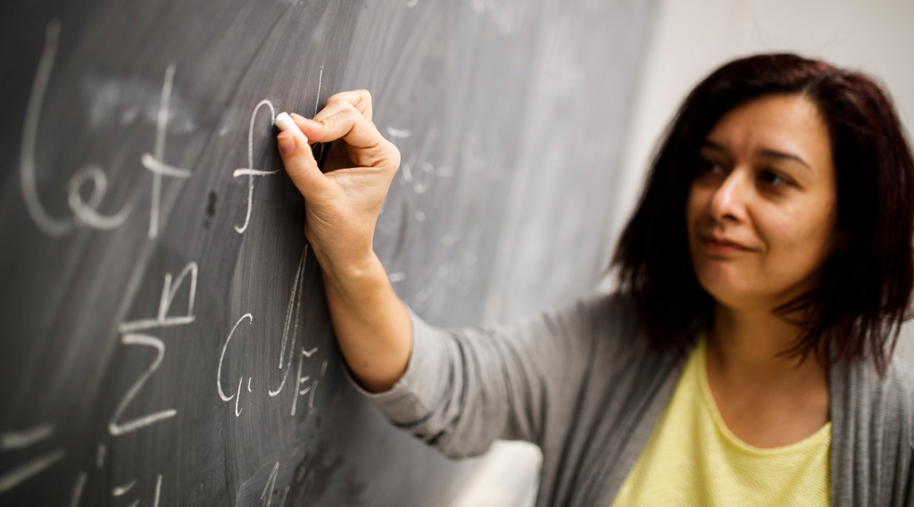 Math Graduate studies student working on blackboard equation.