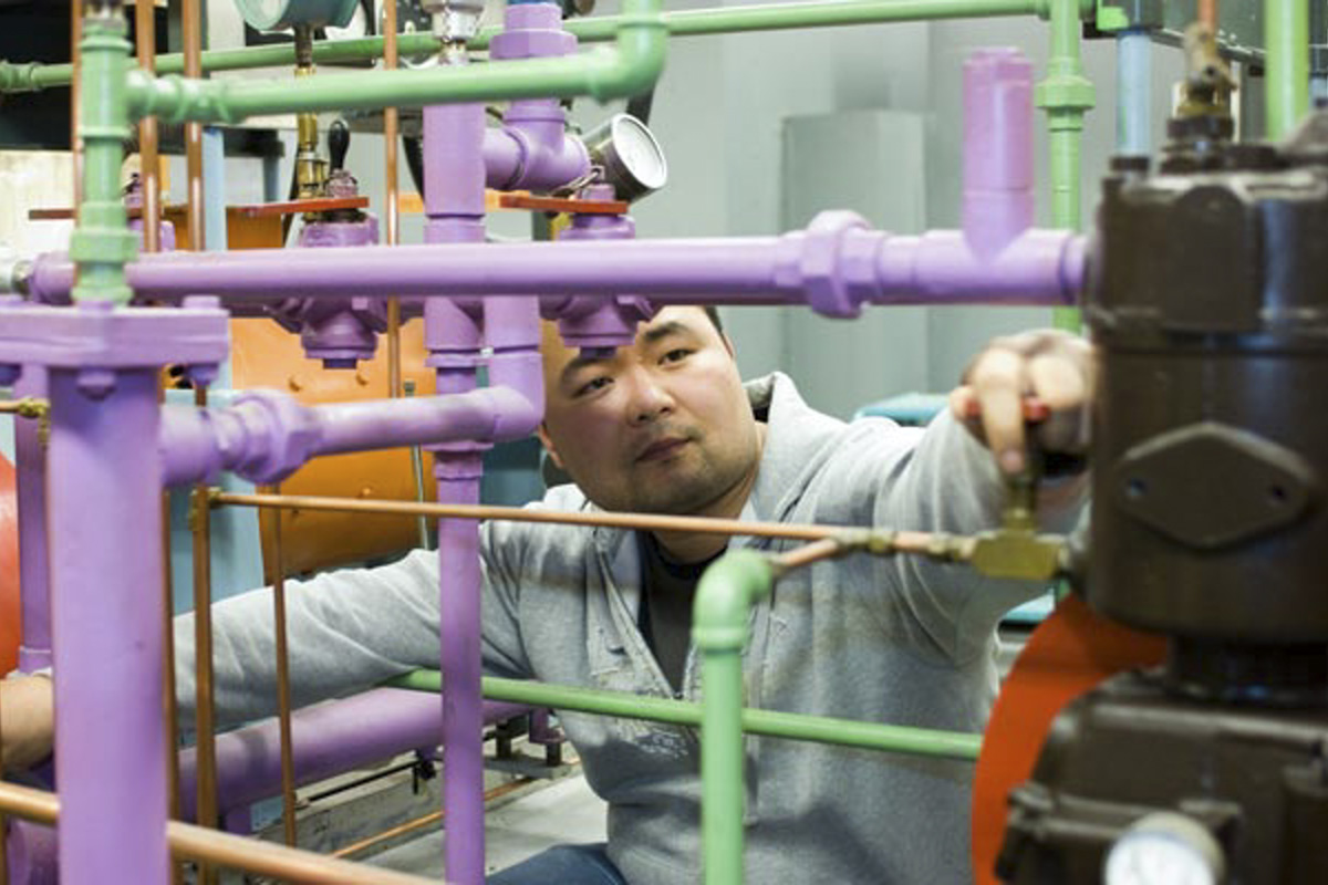A graduate students adjust a lever in a mechanical engineering lab