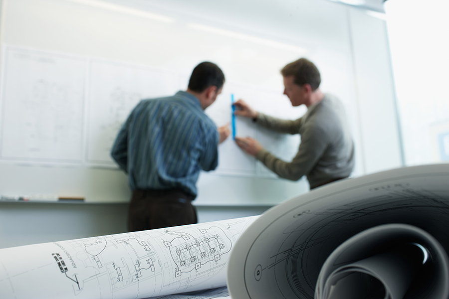 Two industrial engineering students map out a design on a whiteboard