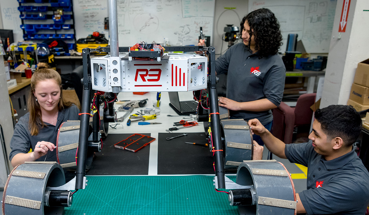 Three students working together in a robotic structure