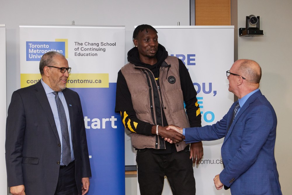 Chris Boucher shakes hand with Gary Hepburn as Mohamed Lachemi stands besides them.